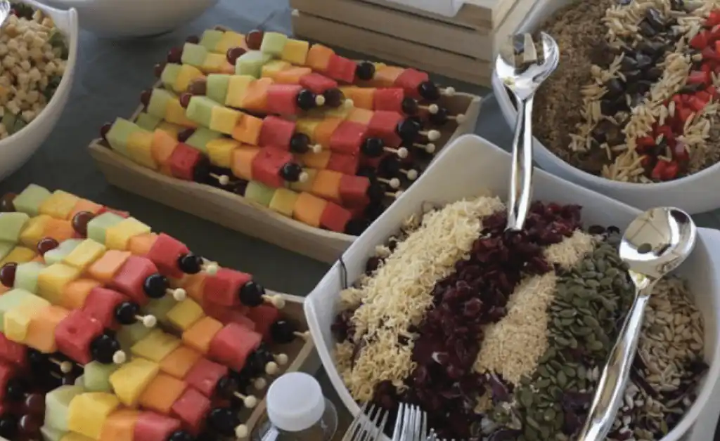 Event buffet with fruit skewers and salads